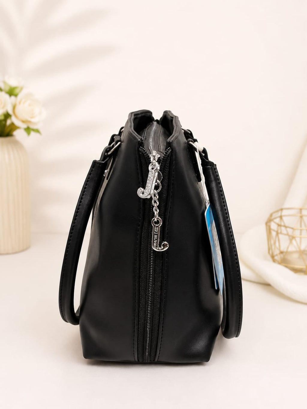 Black structured tote bag – side view with zip detail and charm