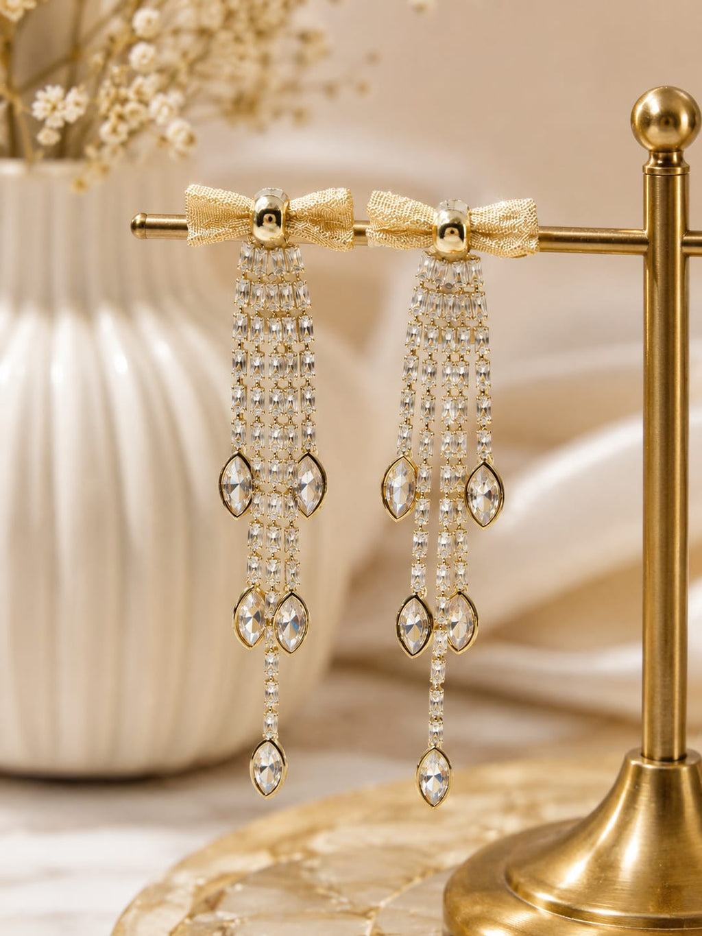 Gold bow crystal tassel drop earrings on display stand