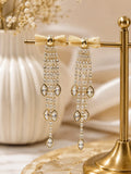 Gold bow crystal tassel drop earrings on display stand
